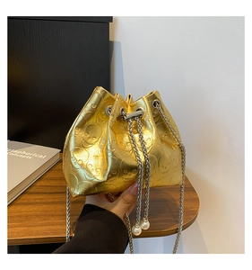 Detail of gold bucket bag with skull embossing, chain strap and pearl drawstring