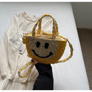 Detail of hand-woven straw bag with smiley face pattern and drawstring closure