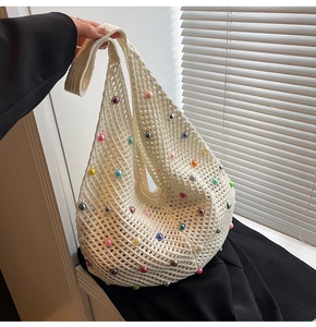 Detail of crochet beach bag with colorful faux pearls and openwork mesh knit pattern