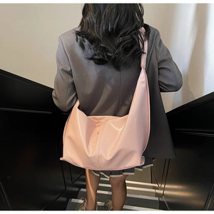 Détail d'un sac hobo rose en cuir PU brillant avec bandoulière large sur un mannequin