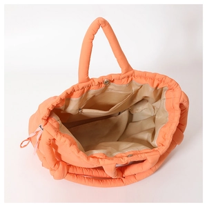 Detail view of large orange quilted tote bag featuring inner zipper pocket and magnetic closure