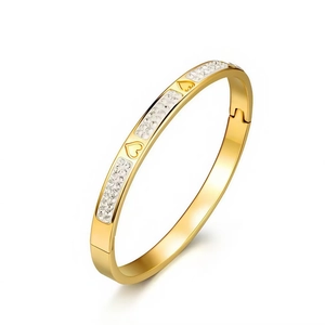 Close-up of gold titanium steel bangle with inlaid crystals and engraved hearts