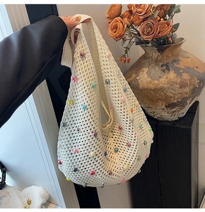 Detail of crochet tote bag with colorful faux pearls and floral background