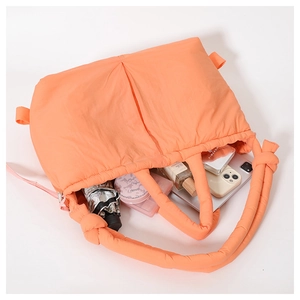 Macro shot of large orange quilted tote bag showcasing spacious interior for essentials