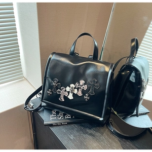 Dettaglio di uno zaino in pelle punk con accenti metallici a croce e toppe strutturate