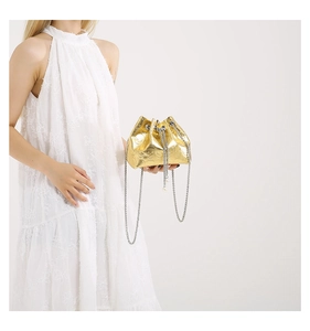 Detail of gold mirror drawstring bucket bag with skull relief and pearl accents
