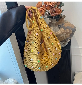 Detail of yellow knit crochet bag with colorful pearls and handmade weave texture
