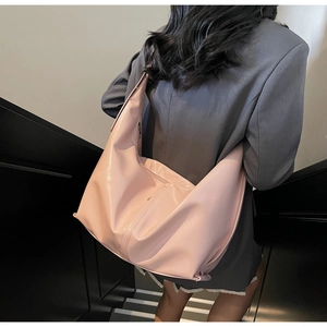 Détail du grand sac hobo rose en cuir brillant porté par un mannequin en extérieur