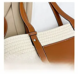 Close-up of woven tote bag featuring brown leather patchwork and white contrast stitching