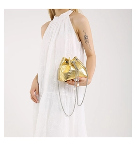 Detail of gold bucket bag featuring embossed skull texture and delicate pearl charms