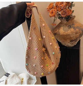 Close-up of beige hollow crochet bag with multi-colored pearls and bohemian mesh texture