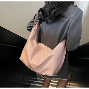 Détail du grand sac hobo rose brillant porté avec un tailleur gris sophistiqué