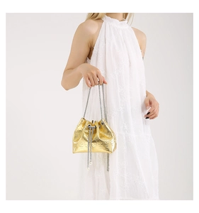 Detail of gold bucket bag with skull pattern, metal chain, and white pearl accents
