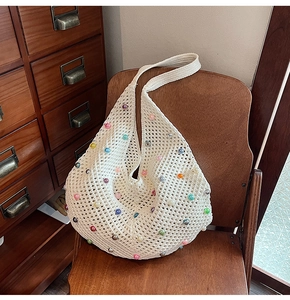 Detail of white crochet beach bag with colorful pearls on a vintage wooden chair