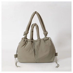 Close-up of khaki green quilted puffer handbag with padded handle and drawstring details