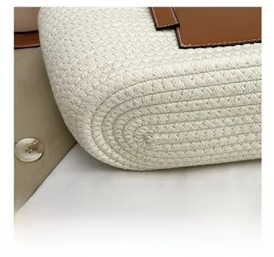 Close-up of beige woven straw tote bag showing brown leather patch and precision stitching
