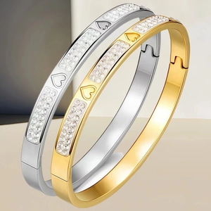 Dettaglio di bracciali in acciaio inossidabile oro e argento con cuori e cristalli
