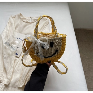 Detail of handmade straw bag featuring a black smiley face and lace bow accessory