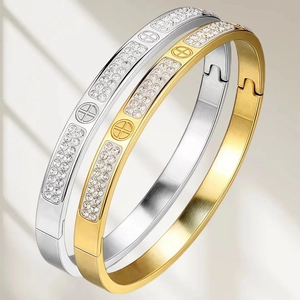 Detail of gold and silver titanium steel bracelets with cross patterns and clear crystals