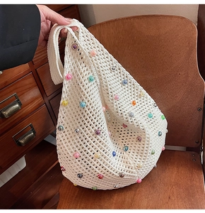 Detailed close-up of white crochet knit bag with colorful pearl beads on vintage chair
