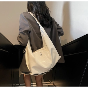 Détail du sac hobo en cuir PU blanc brillant porté par un mannequin dans un escalier
