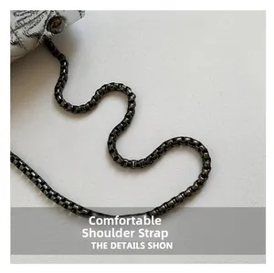 Close-up of gunmetal box chain strap on silver quilted metallic leather handbag