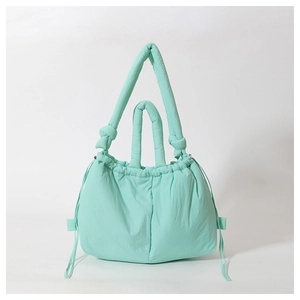Detail of mint green quilted nylon puffy shoulder bag with drawstring closure and knotted straps
