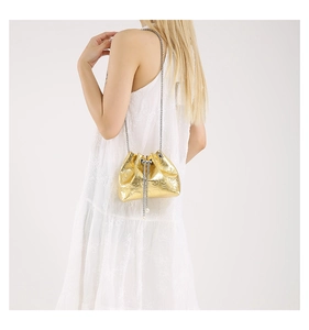 Detailed view of mini gold drawstring bucket bag with skull motif and pearl accents