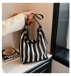 Detail of black and white striped mesh tote bag with leather trim and hobo style structure