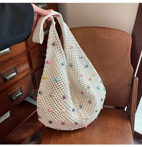 Close-up of white crochet tote bag with colorful bead accents and hollow mesh texture