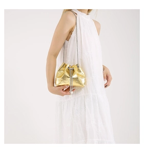 Detail of gold metal bucket bag with skull relief, pearl drawstrings and chain strap