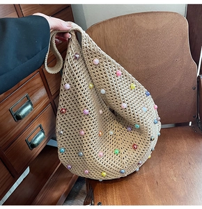 Detail of beige crochet hobo bag featuring colorful pearl beads and hollow knit texture