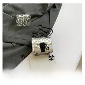 Silver quilted mini chain bag detail with metal lock and smartphone for size reference