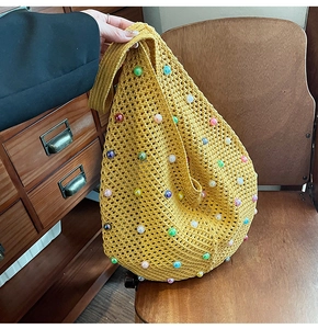 Close-up of yellow knit beach bag featuring vibrant multi-colored pearl embellishments