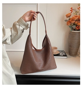 Detailed close-up of high-quality dark brown woven leather texture on a stylish hobo tote bag