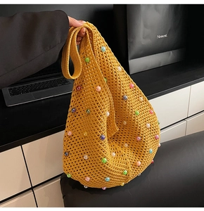 Detail of yellow knit tote bag with colorful pearl embellishments and hollow texture