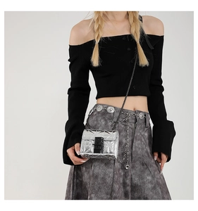 Detail of silver quilted mini crossbody bag with metal chain on a female model