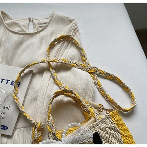 Detail of woven straw bag with yellow accents, pearl handle, lace trim and braided strap