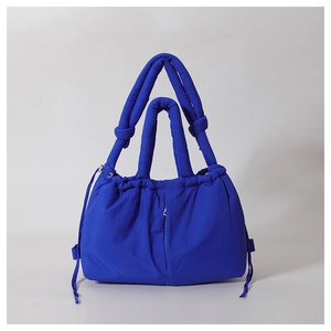 Detail of royal blue quilted puffer handbag with padded handles and drawstring closure