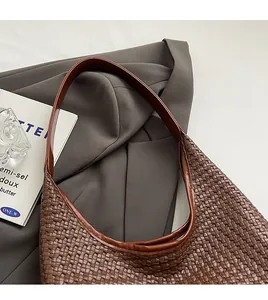 Detail of dark brown woven leather hobo bag showing fine texture on a grey suit jacket