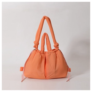 Detail of a bright orange padded nylon tote bag with drawstring closure and handles