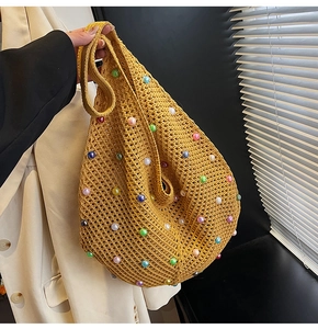 Detail of yellow hollow knit tote bag with vibrant pearl embellishments and woven texture