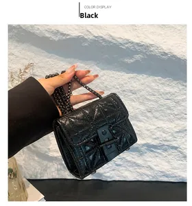 Detail of black quilted crossbody bag with glossy finish and metal chain strap