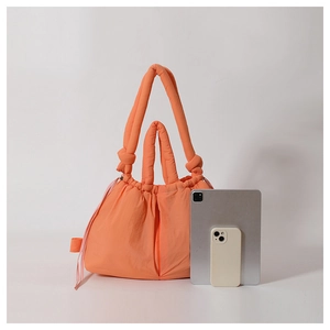 Bright orange puffer tote bag showing large capacity with tablet and phone comparison
