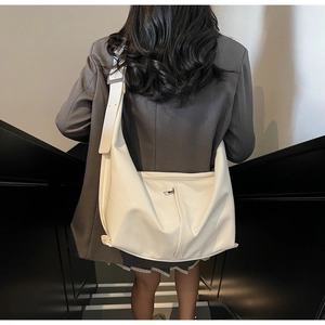 Détail du sac hobo en cuir PU blanc brillant avec fermeture éclair porté par un mannequin