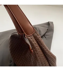 Detailed close-up of handmade stitching and woven texture on a brown tote bag