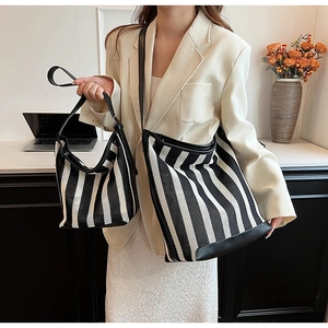 Detail of black and white striped mesh tote bag with leather trim and matching small pouch