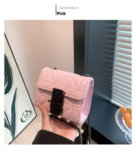 Detail of pink quilted mini bag with black metal lock and chain strap held by hand