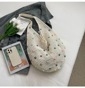Close-up of white hollow knit tote bag with colorful pearl accents on a lifestyle background