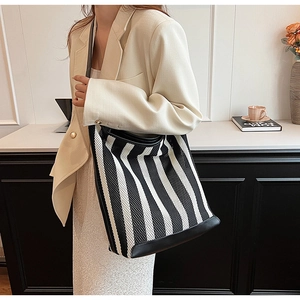 Detail of black and white striped mesh tote bag with reinforced leather edges